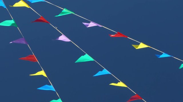 Multi colored flags on the blue sky.
Pennants moved for the wind, symbol of celebration and fun.