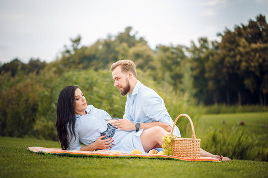 young couple having a picnic in a city park, a woman is expecting a baby.