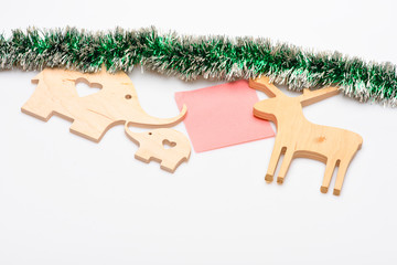 Decorations for Christmas holidays made out of natural materials and tinsel. Wooden deer and elephant toys or decoration with paper for note on white background. Christmas decorations concept