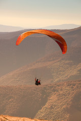 Paragliding in the Ukrainian Carpathians. People in parachute mountains. Autumn landscapes on a sunny day. Equipping for paragliding.Sportsmen.Sunsut and sunrise