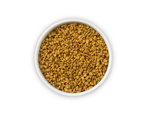 Fenugreek seeds in a wooden bowl isolated on white. Fenugreek seeds isolated on white background. Top view. Fenugreek with copy space for text.