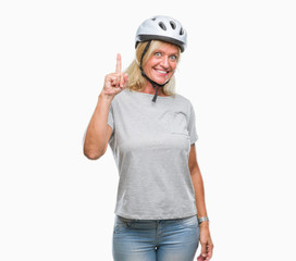 Middle age caucasian cyclist woman wearing safety helmet over isolated background pointing finger up with successful idea. Exited and happy. Number one.