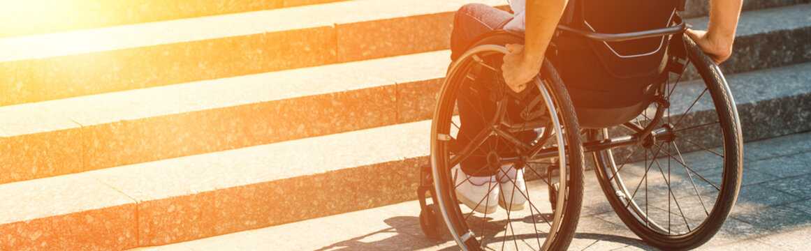 cropped image of disabled man using wheelchair on street and stopping near stairs without ramp