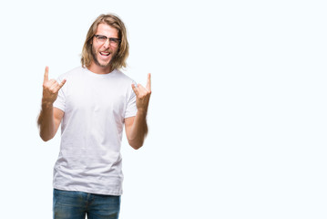 Young handsome man with long hair wearing glasses over isolated background shouting with crazy expression doing rock symbol with hands up. Music star. Heavy concept.