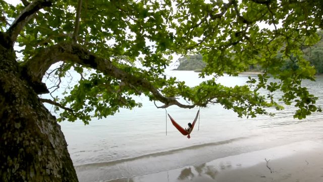 Woman relaxing in hammock on tropical beach
