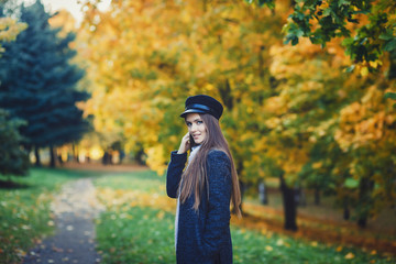 Beautiful smiling girl in stylish fashion clothes in autumn park.
