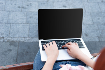 cropped image of freelancer using laptop with lank screen on street