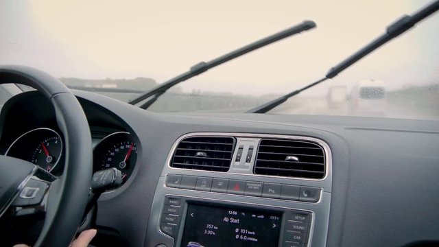 Frauenhand bedient Scheibenwischer auf der Autobahn