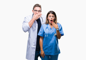 Young couple of doctor and surgeon over isolated background shocked covering mouth with hands for mistake. Secret concept.