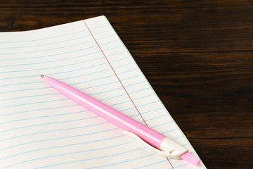 Education concept back to school - pink pen on book background close-up, mock-up, copy space