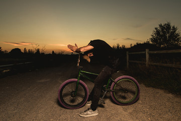 Young man standing bmx bike. BMX rider with and a sunset
