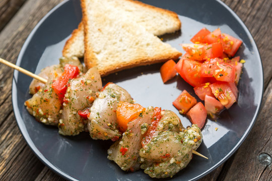 Raw skewer of meat on a plate.