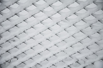Beautiful winter. White snow on wire metal mesh fence. Blurred snowy nature on winter time, close up view. Texture of snow covered on the fence. Winter time.