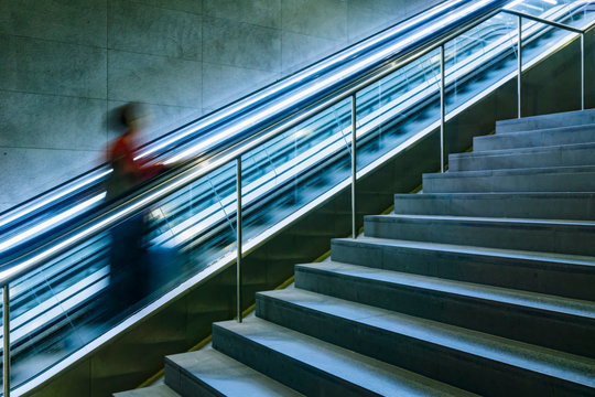Woman going up a moving escalator at a railway station, Berlin, Germany