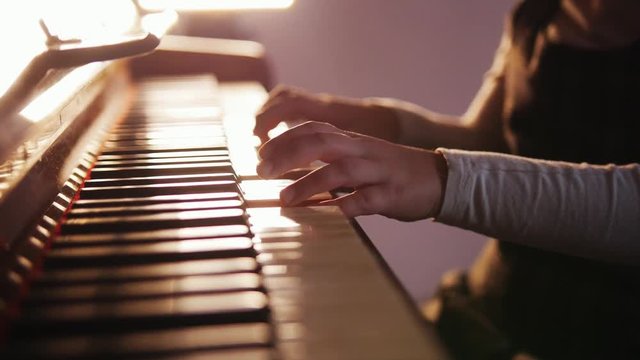 Child playing piano. Close up on piano keys, child hands and fingers. Slider view of playing