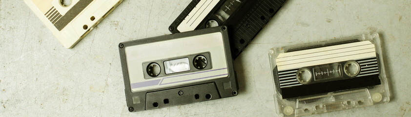 A lot of old audio cassettes. Gray old background. Vintage toned and retro color stylized. Horizontal photo. Flat top viev - obrazy, fototapety, plakaty