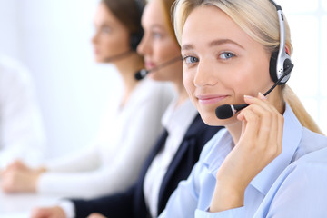 Call center. Group of operators at work. Focus at brunette business woman in headset
