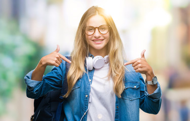 Young beautiful blonde student woman wearing headphones and glasses over isolated background looking confident with smile on face, pointing oneself with fingers proud and happy.