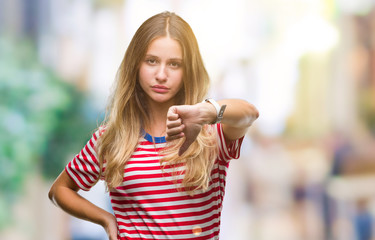 Young beautiful blonde woman over isolated background looking unhappy and angry showing rejection...