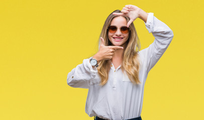 Young beautiful blonde woman wearing sunglasses over isolated background smiling making frame with hands and fingers with happy face. Creativity and photography concept.