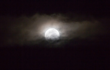 Fototapeta na wymiar The moon in the haze of the clouds at night