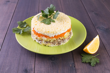 Festive layered round salad with vegetables and salmon fish Mimosa on a plate on a wooden background