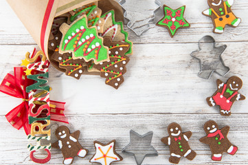 Beautiful Christmas composition and decoration with baked Christmas gingerbread cookies in paper bag on light wooden background, flat lay, top view, copy space (text space)