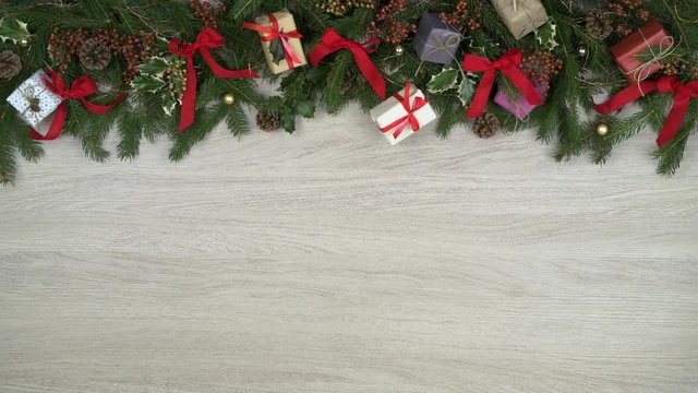 Looping overhead decoration top frame on light wood background with pine cones,gifts,red gold ribbons,blinking lights.Text or logo copy space.Vertical top view.Xmas holiday season social card.4k video