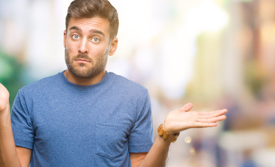 Young handsome man over isolated background clueless and confused expression with arms and hands...