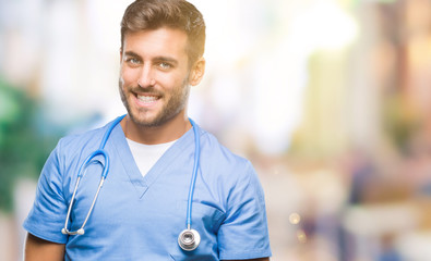 Young handsome doctor surgeon man over isolated background looking away to side with smile on face, natural expression. Laughing confident.