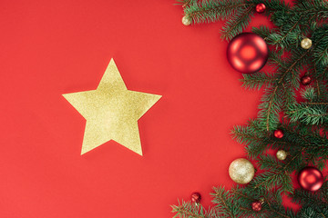 flat lay with pine tree branches with red and golden christmas balls and golden star isolated on red