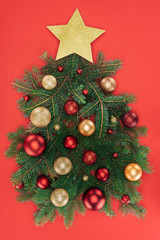 top view of pine tree branches, golden star and christmas balls arranged in christmas tree isolated on red