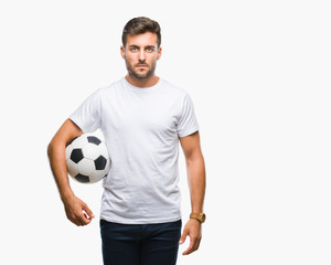 Young handsome man holding soccer football ball over isolated background with a confident...