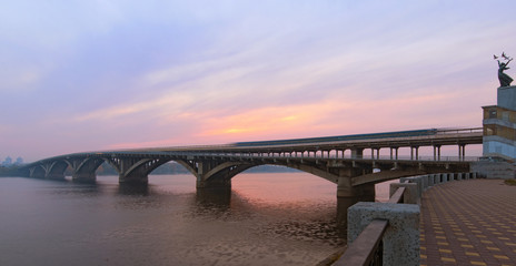 Classic wide-angle view of Merto Bridge with old underground (subway) train over Dnipro River. Scenic autumn landscape during sunrise. Kyiv, Ukraine