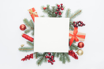Fototapeta na wymiar top view of pine tree branches, christmas decorations and gifts with square blank space in middle isolated on white