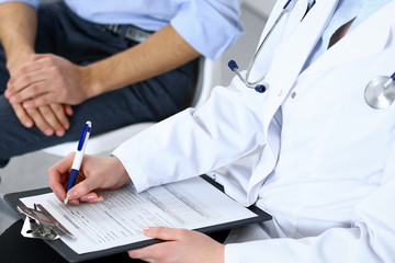 Female doctor holding application form while consulting man patient in hospital. Medicine and healthcare concept