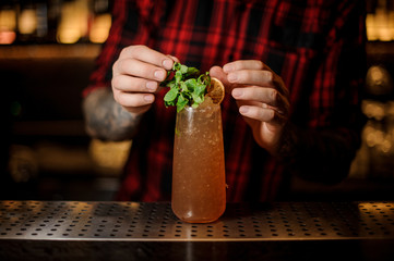 Bartender decorating high ball glass filled with fresh Cobras Fang cocktail