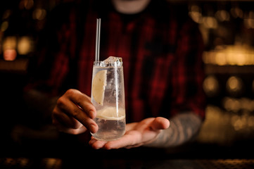 Bartender holding long drink glass filled with Tom Collins cocktail