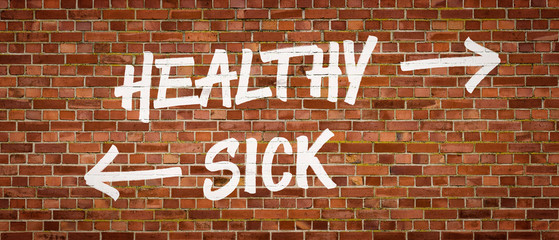 Healthy or Sick written on a brick wall