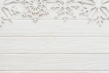 Fotobehang flat lay with decorative snowflakes on white wooden tabletop © LIGHTFIELD STUDIOS