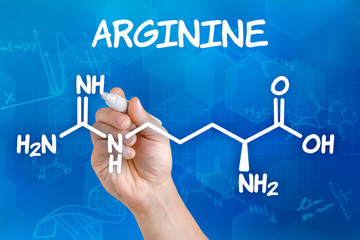 Hand with pen drawing the chemical formula of arginine