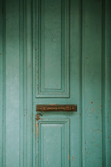 Old cracked wooden turquoise entrance door with golden brass handle in oldest Denmark village Ribe