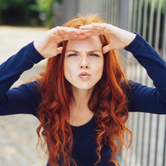 Young woman squinting while shading her eyes