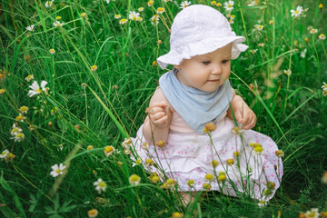 Baby girl sitting in the green grass.