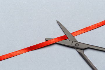 Grand Opening illustrated with  scissors and a red ribbon on a gray background