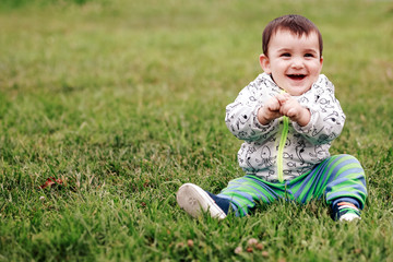 first steps of cute baby boy on footpath among greens