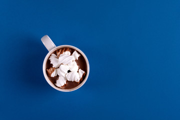 Chocolat chaud avec des bonbons à la guimauve sur fond de papier bleu. Vue de dessus. Espace de copie