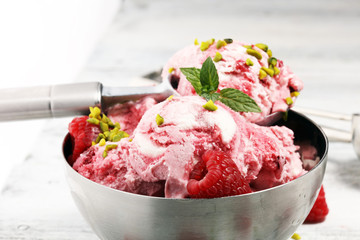 Raspberry ice cream scoop with chopped nuts and white chocolate on a rustic background