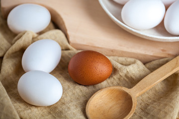 white and brown eggs on a wooden table, a towel and a wooden spoon