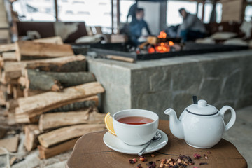 Cup of tea teapot on wood table in restaurant and fireplace is back